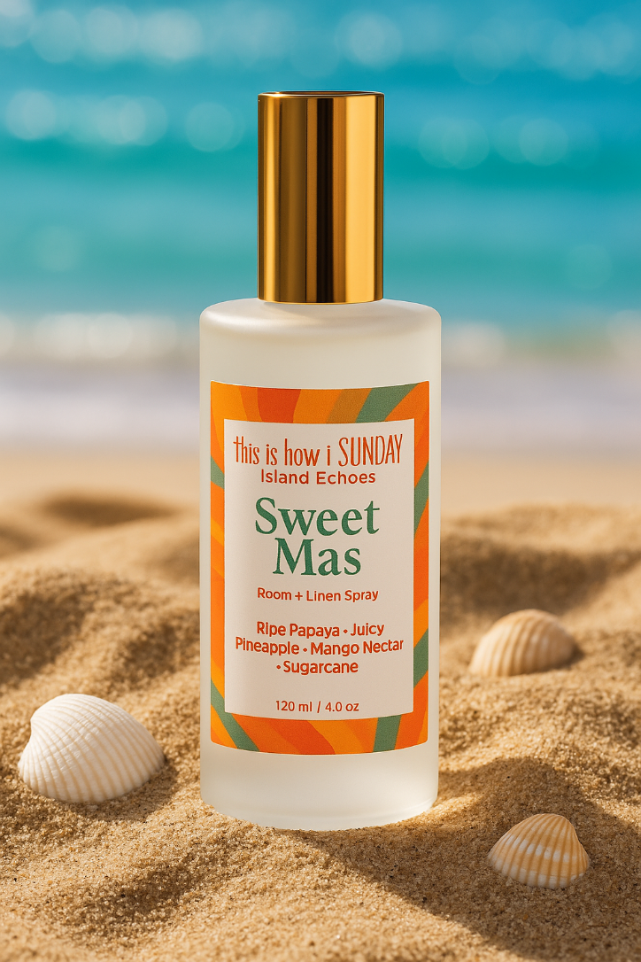Bottle of 'Sweet Mas' room and linen spray on a sandy beach with ocean in the background